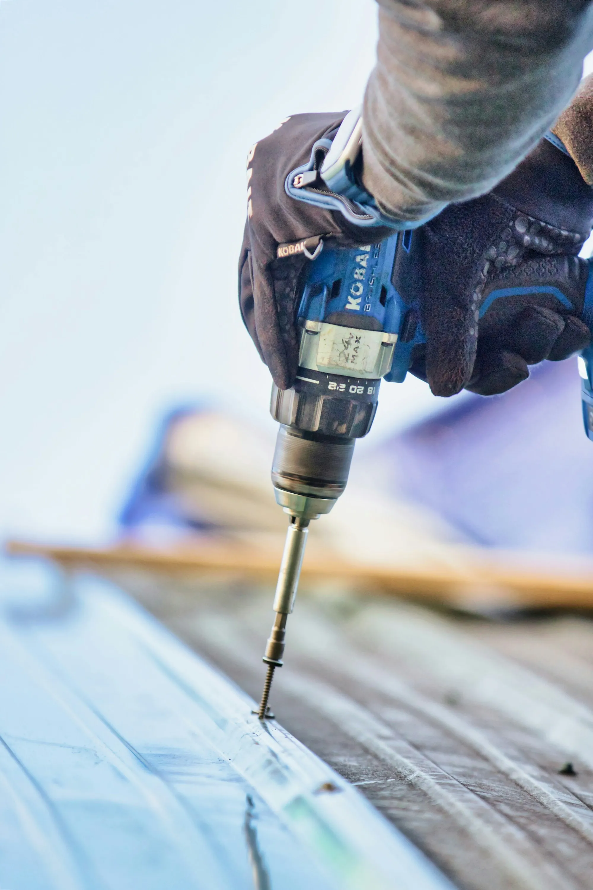Gloved hand driving a fastener with a drill