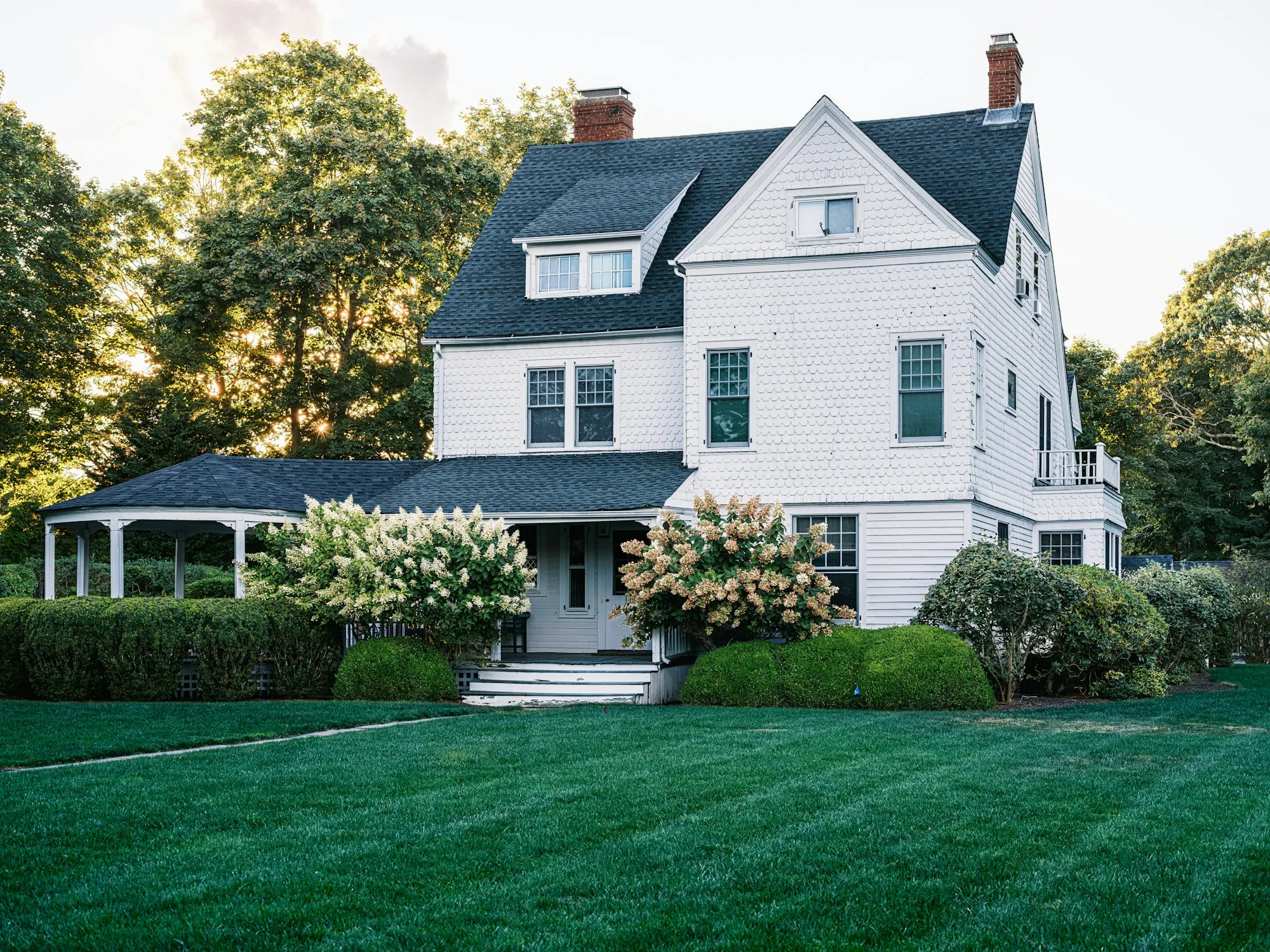 Large white house with a dark shingle roof and a front lawn