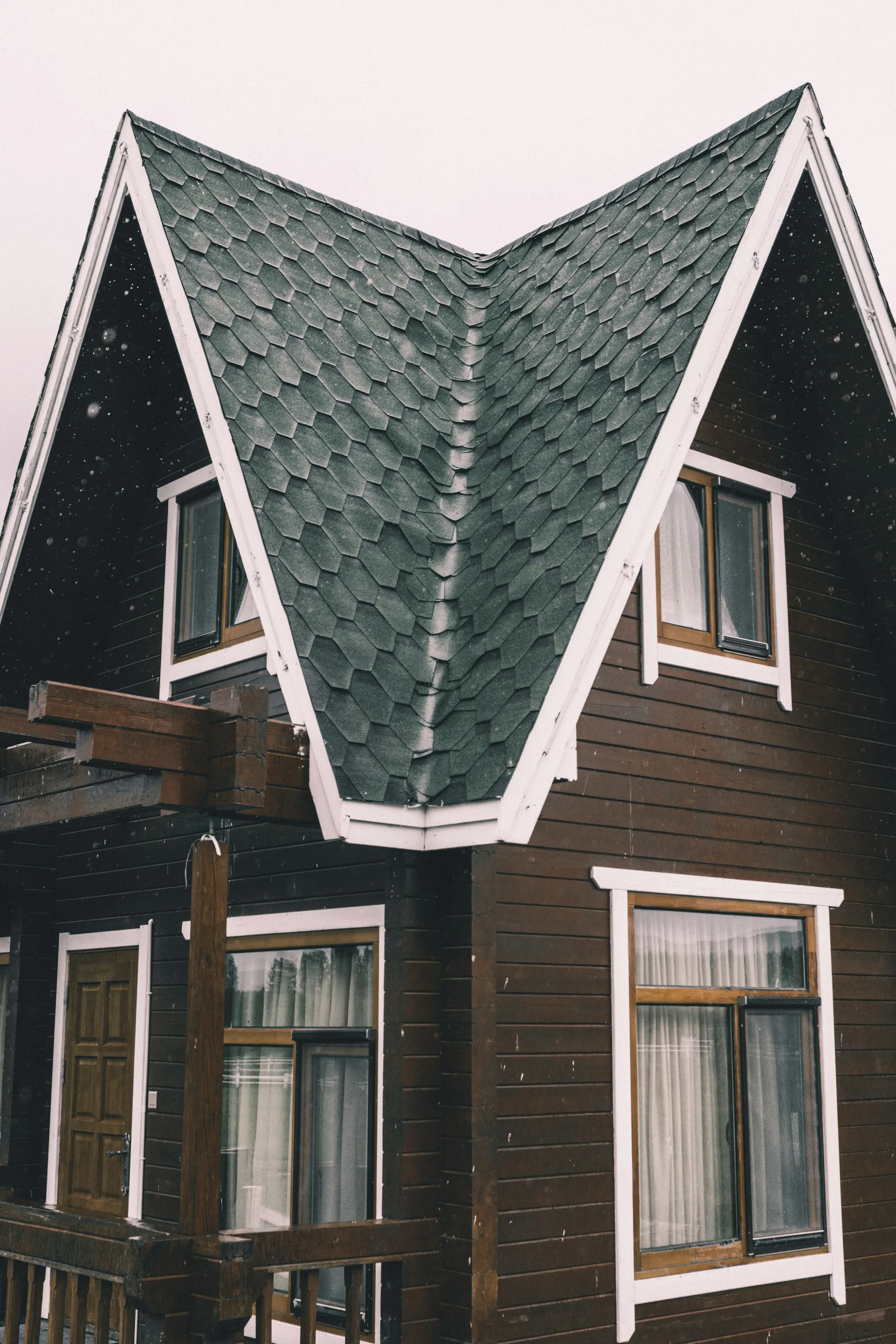 Gable end of a house clad in dark shingle with white trim