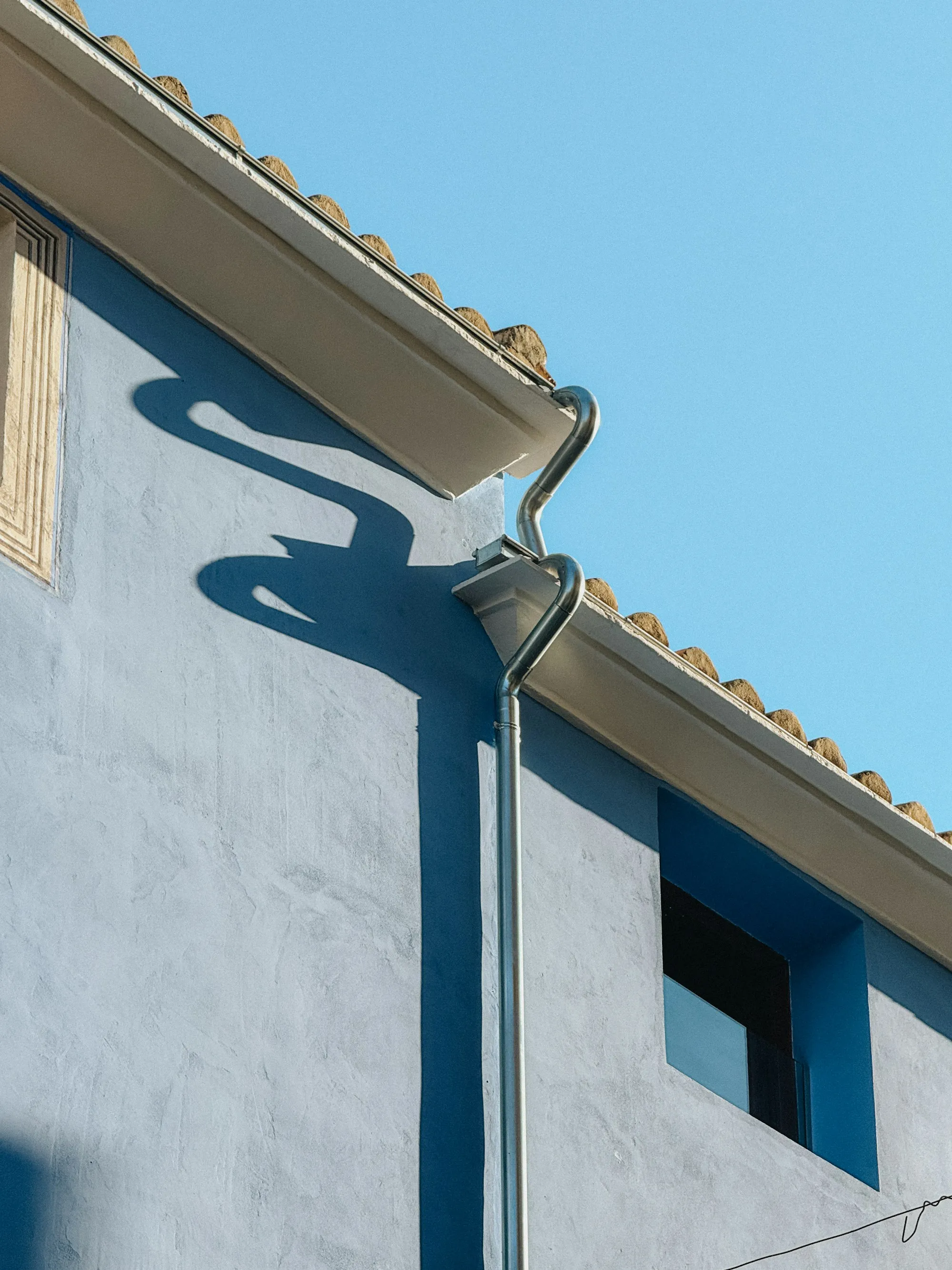 Gutter and downspout elbow on a painted wall
